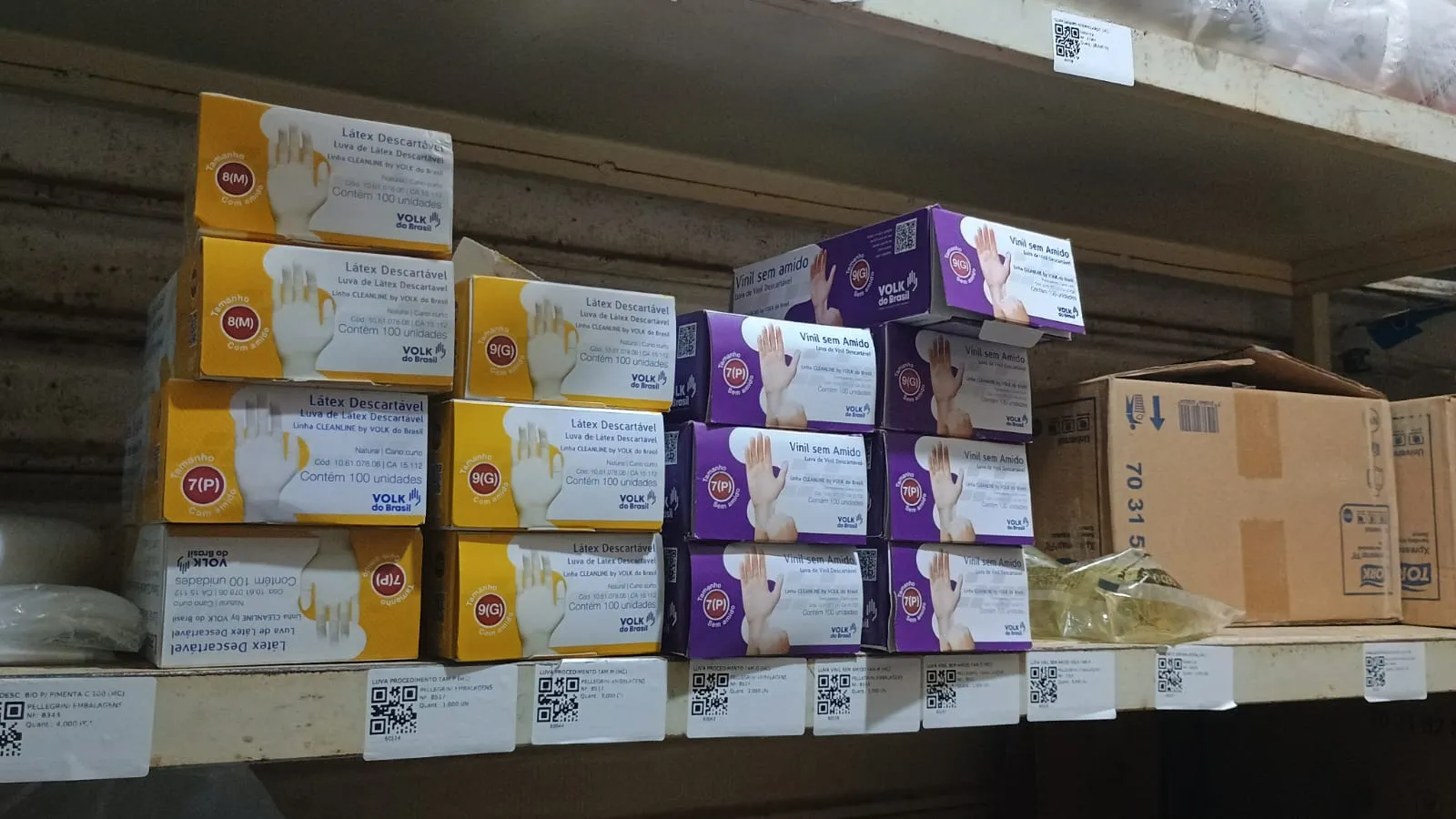 Prateleira com caixas de luvas, cada uma com etiqueta QR na frente
